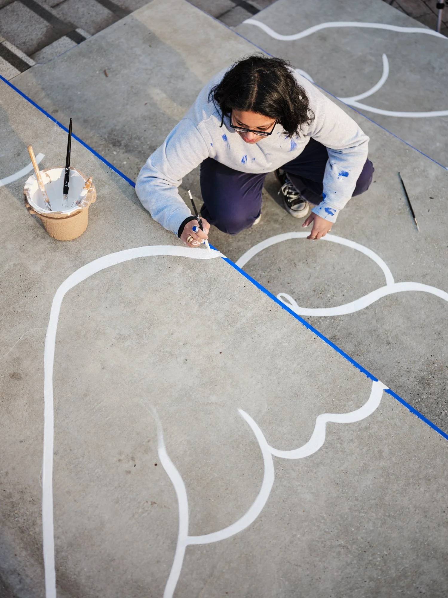 Laxmi Hussain painting large-scale body line work on the floor